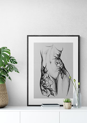 Framed black and white floral line art of a female torso on a modern sideboard with plants.